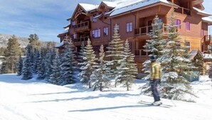 A multi-story wooden lodge with balconies, surrounded by snow-covered trees. - Mountain Thunder (Breckenridge)