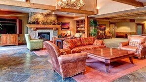 A spacious living room with a fireplace, leather sofas, and a chandelier. - Mountain Thunder (Breckenridge)