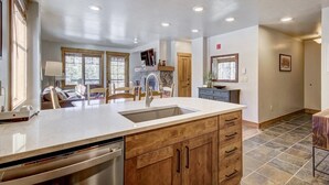 A spacious kitchen with a large island, wooden cabinets, and a built-in dishwasher. - Mountain Thunder (Breckenridge)