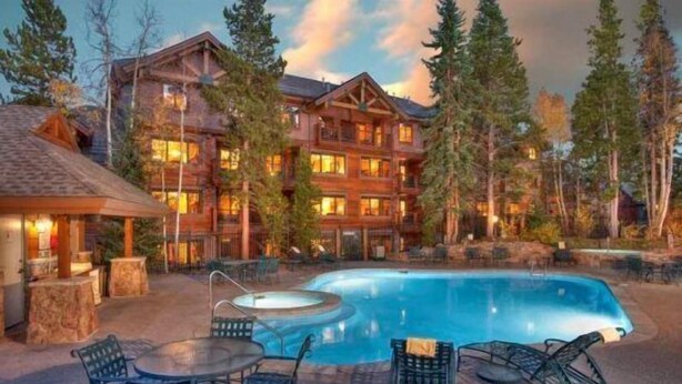 A lodge with a pool, outdoor seating, and a large building with multiple windows. - Mountain Thunder (Breckenridge)