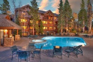 A lodge with a pool, outdoor seating, and a large building with multiple windows.