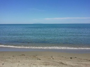 A beach with a clear view of the ocean and a distant mountain.