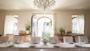A dining table set for six with white tablecloths, clear glassware, and a decorative pitcher.