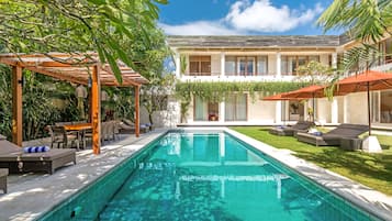 Una piscina al aire libre, sillones reclinables de piscina