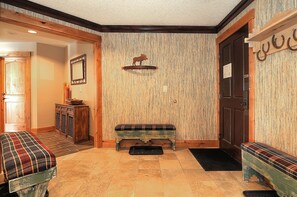A hallway with a bench, a wooden door, and a wall-mounted shelf with a moose decoration. - Southern Comfort (Breckenridge)