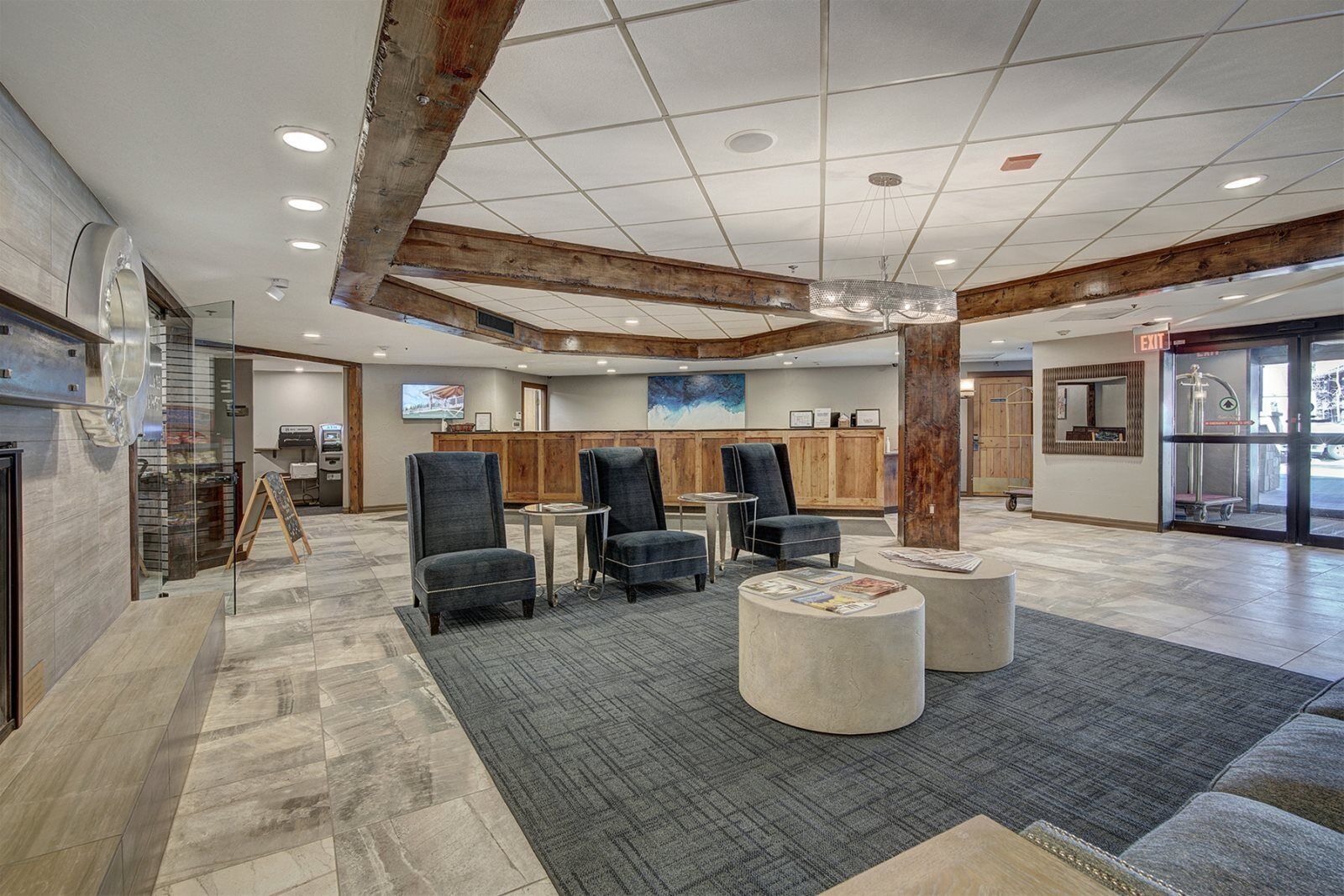 Un hall d’entrée spacieux avec un plafond haut, des poutres en bois et un coin salon agrémenté de fauteuils et de poufs.
