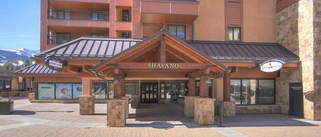 Entrada de hotel com área coberta, placa com a inscrição 'SHAVANO' e sinalização indicando 'ALUGUEL'.