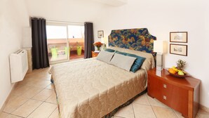 A hotel room with a bed, a nightstand, a lamp, a fruit bowl, and a view of the balcony. - Spacious 4 BR apartment, Taormina center, multiple terraces w. stunning views  (Taormina)