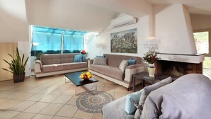 A spacious living room with a beige sofa set, a coffee table with fruit, a patterned rug, and a fireplace. - Spacious 4 BR apartment, Taormina center, multiple terraces w. stunning views  (Taormina)