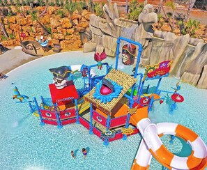 A water park with a pirate-themed play structure, including slides and a shipwreck.