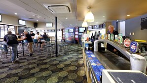 A bar area with stools and a counter with taps. - Lakes and Ocean Hotel Forster (Forster)