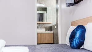 A hotel room with a bed, a bathroom with a mirror, and a sink. - Lakes and Ocean Hotel Forster (Forster)