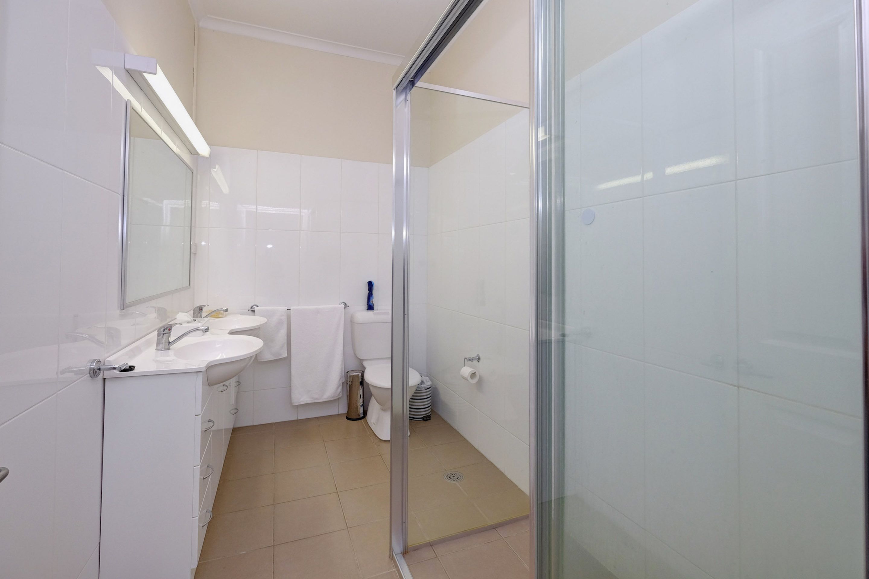 Ein modernes Badezimmer mit Duschkabine aus Glas, Waschbecken in Weiß und Toilette.