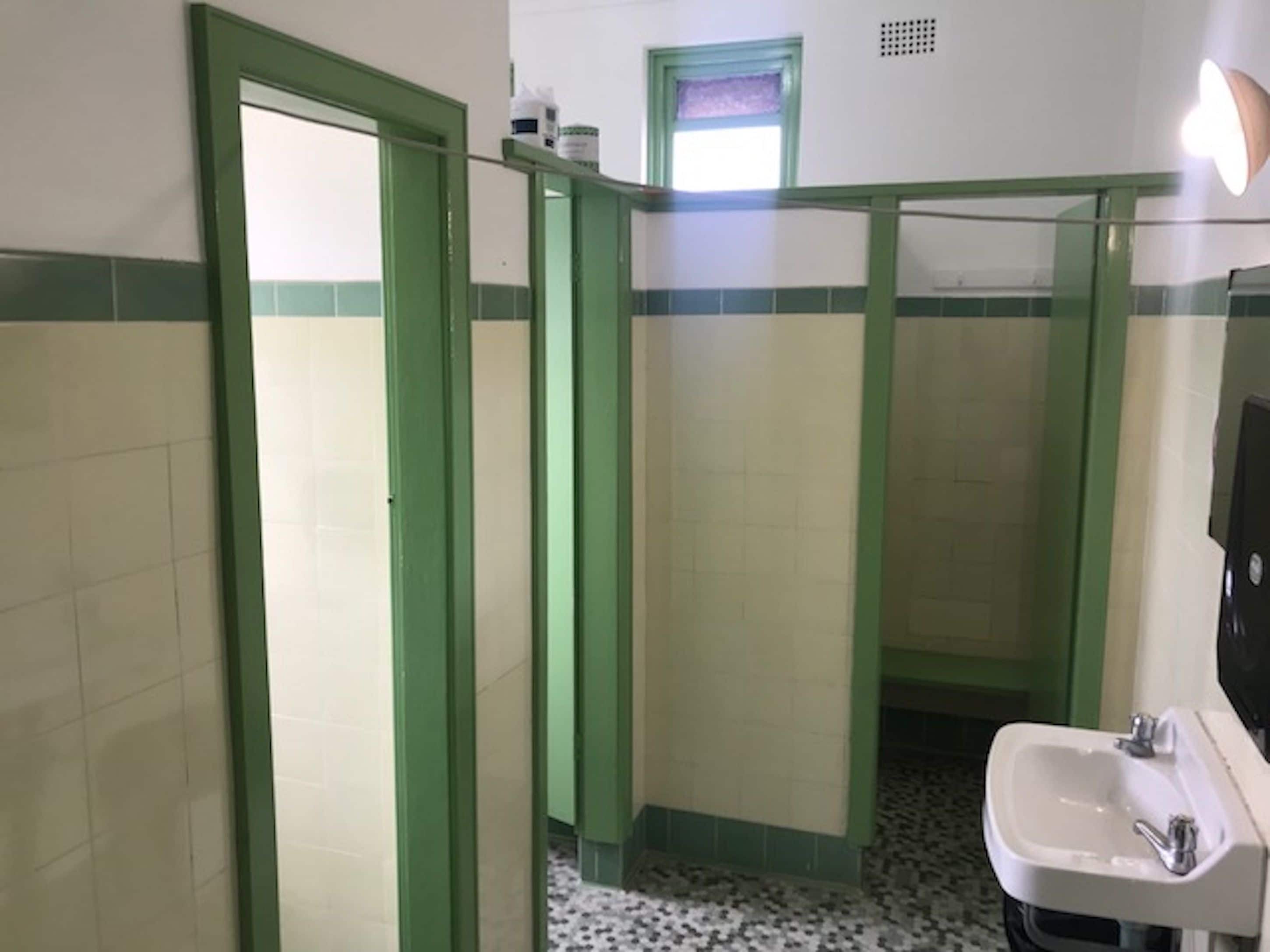 A bathroom with green-tiled walls, a white sink, and a mirror.