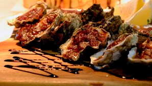 A variety of seafood dishes on a wooden board, including oysters and other seafood items. - Lakes and Ocean Hotel Forster (Forster)