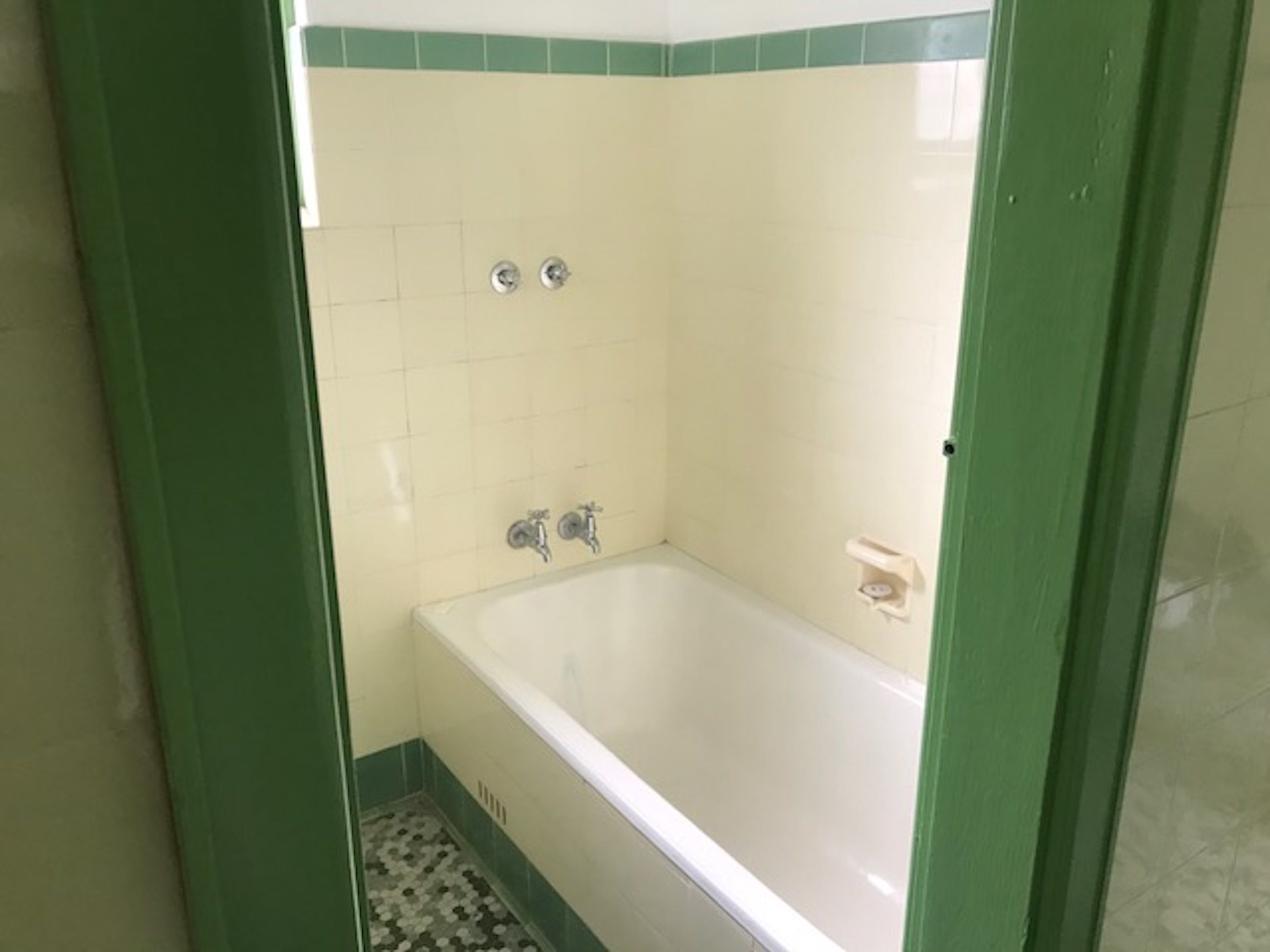 A bathroom with a bathtub, two faucets, and a soap dish.