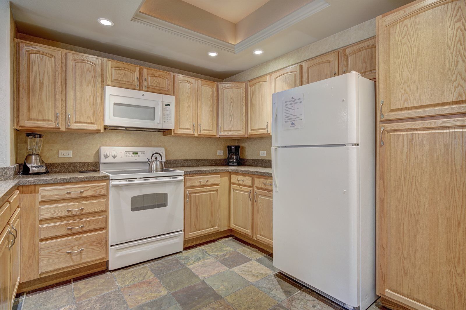 A kitchen with wooden cabinets, a white refrigerator, a stove, and a microwave.