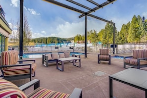 Um pátio externo com área de estar, piscina e vista para uma paisagem nevada.