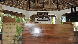 A reception desk at Subli Beach Resort with a wooden counter, a signboard, and a reception area. - Coco Paradise Beach Resort (Currimao)