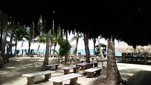A beachside area with stone benches and thatched umbrellas, overlooking the sea. - Coco Paradise Beach Resort (Currimao)