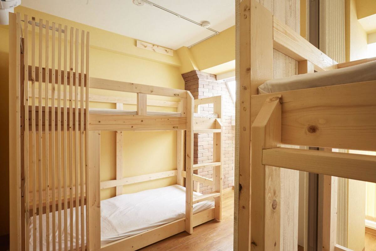 Quarto com beliche, parede de tijolos e janela.