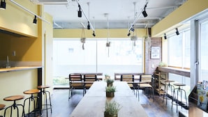 A café with a long wooden table, multiple bar stools, hanging plants, and a sign that reads "FOLLOW SIGN COFFEE". - Bed & Breakfast RENGA – Hostel (Tokyo)