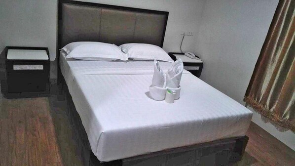 A hotel room with a neatly made bed, two bedside tables, and a telephone on one of the tables.