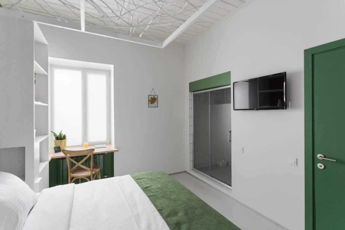 Une chambre à coucher comprenant un lit, un bureau avec une chaise, une télévision, une armoire et une fenêtre.