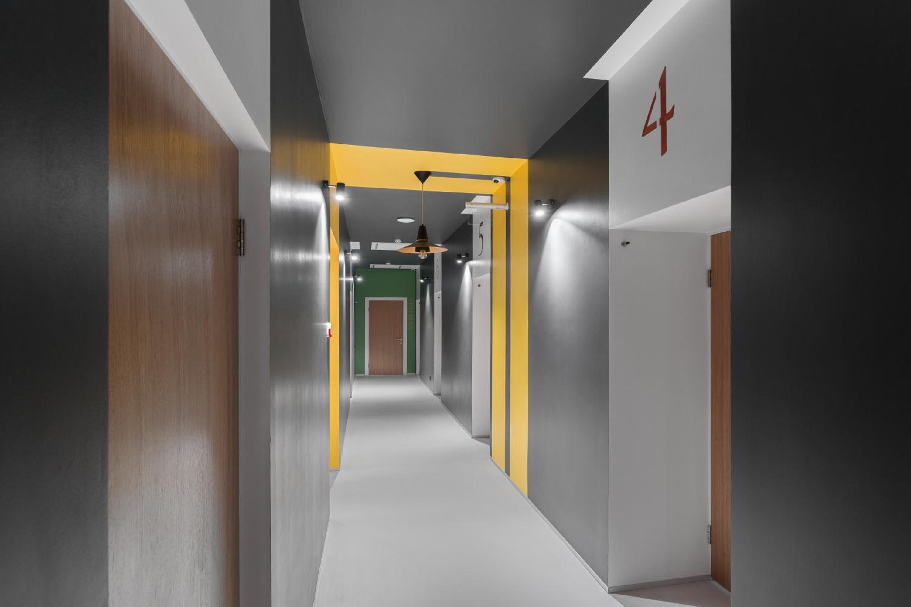 A modern hallway with a central corridor, flanked by walls with metallic and wooden finishes, and a number '4' sign on the right.