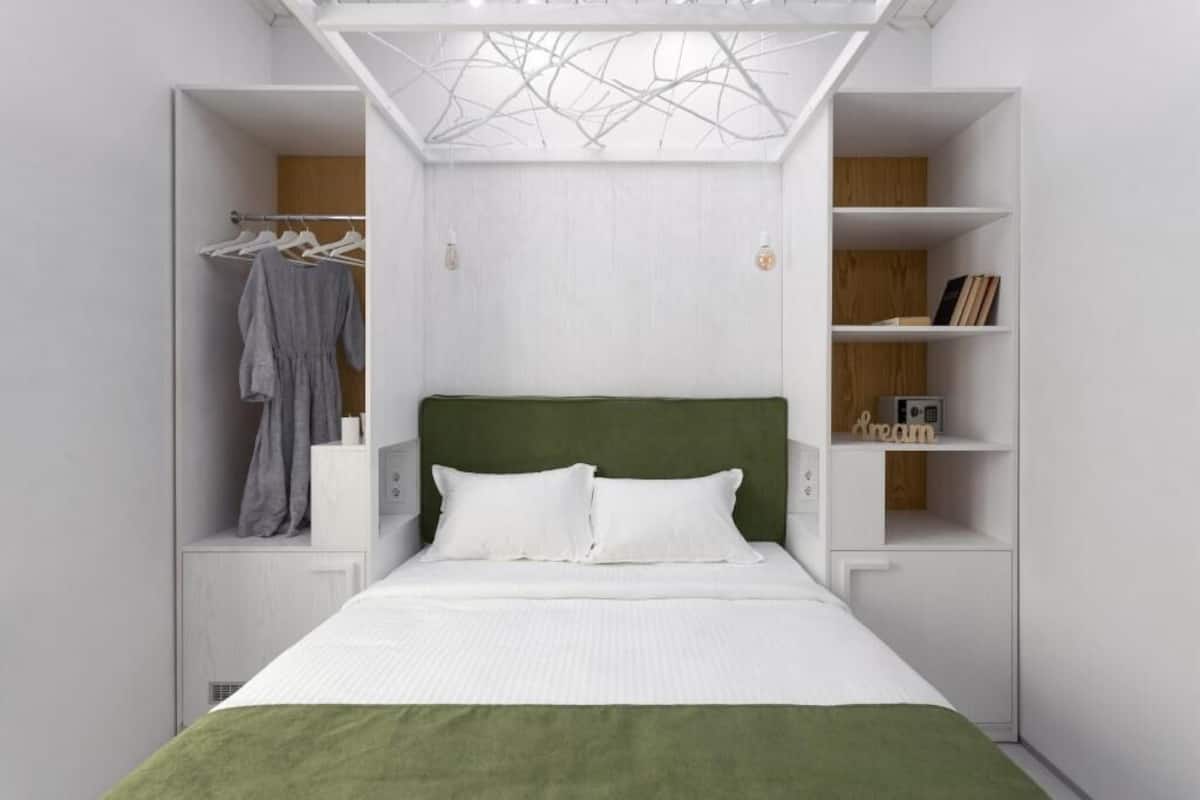 Une chambre à coucher avec un lit, une armoire et une étagère contenant des livres et une lampe.