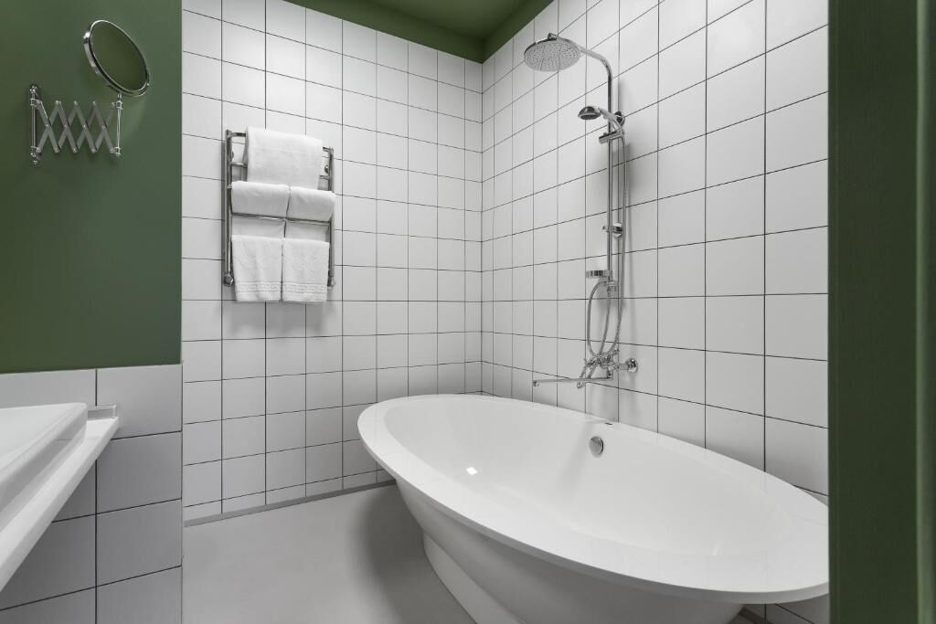A modern bathroom with a freestanding bathtub, a showerhead, and a towel rack with multiple towels.