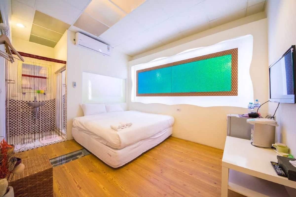 A modern hotel room with a bed, a TV, and a small table.