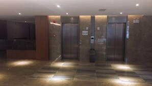 Een modern lifthok met marmeren vloer en een receptiebalie links.