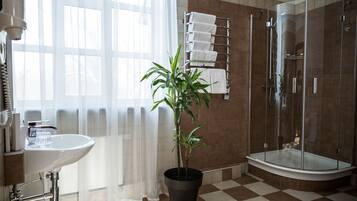 A bathroom with a sink, a potted plant, a glass shower enclosure, and a towel rack.