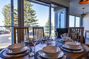 Una mesa de comedor preparada para cuatro personas, con vistas a árboles y una carretera.