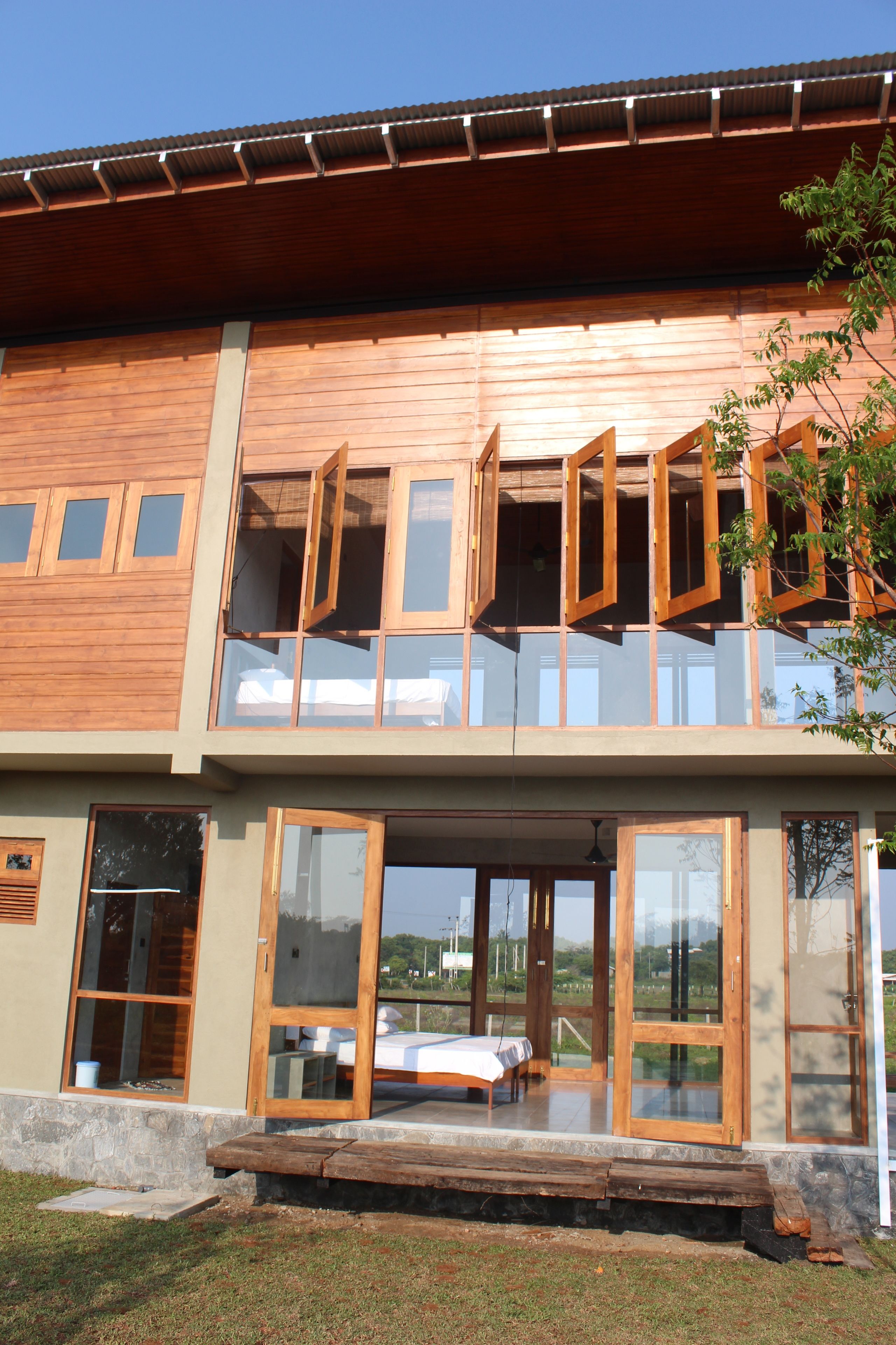 Una casa moderna de dos pisos con grandes ventanales y fachada de madera.