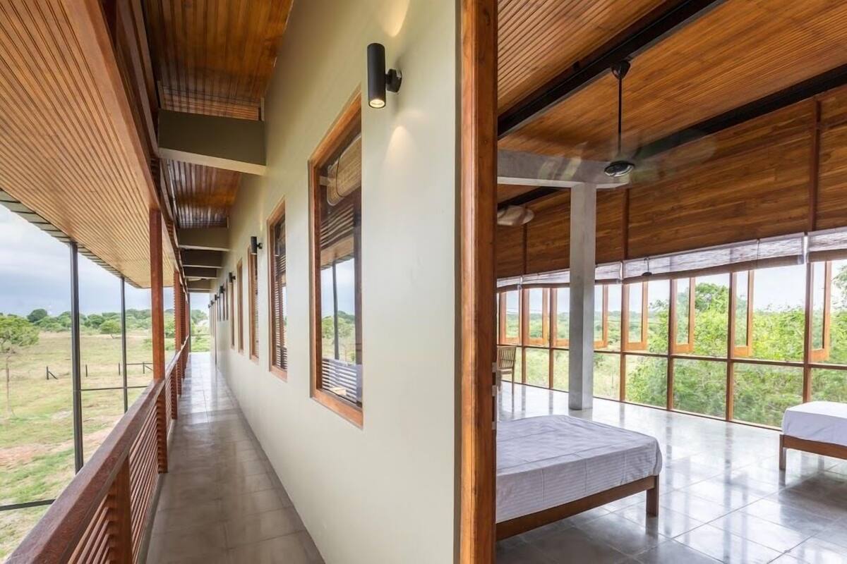 A corridor with wooden ceiling beams, large windows, and a bed in a room.