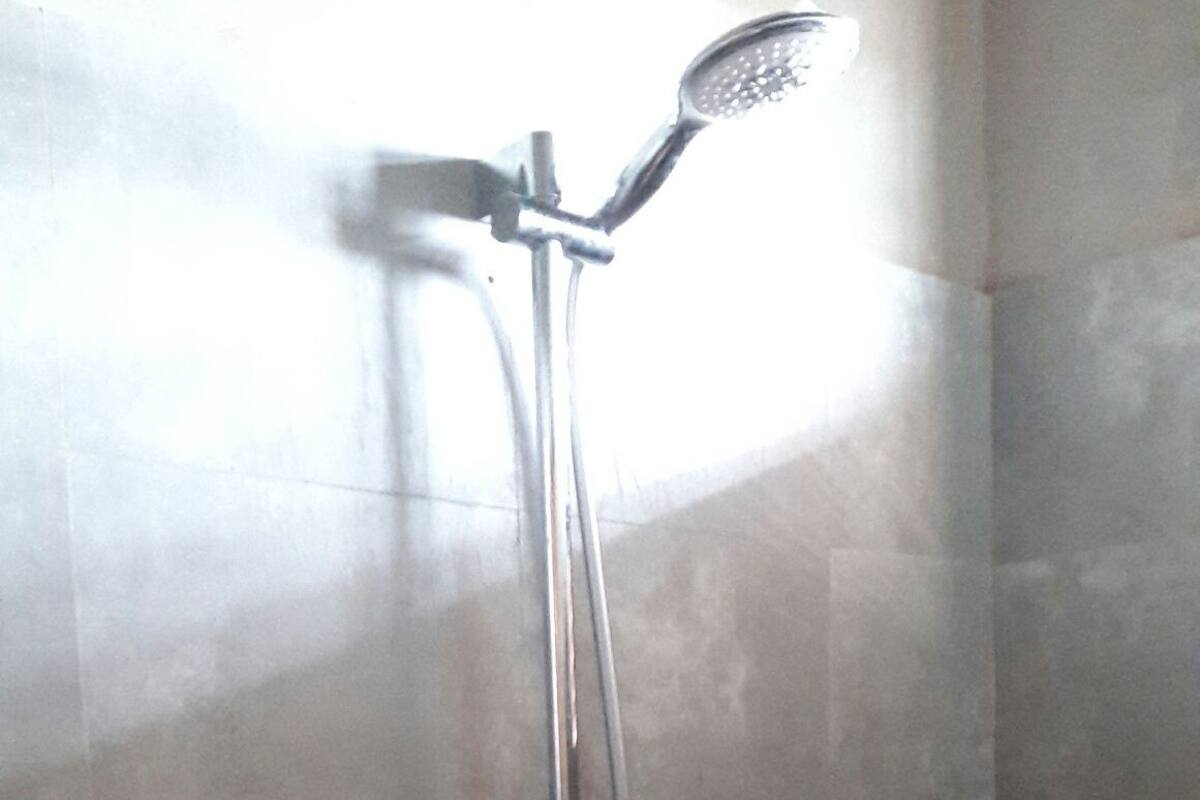 A shower with a handheld showerhead and a wall-mounted faucet.
