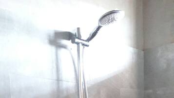 A shower with a handheld showerhead and a wall-mounted faucet.