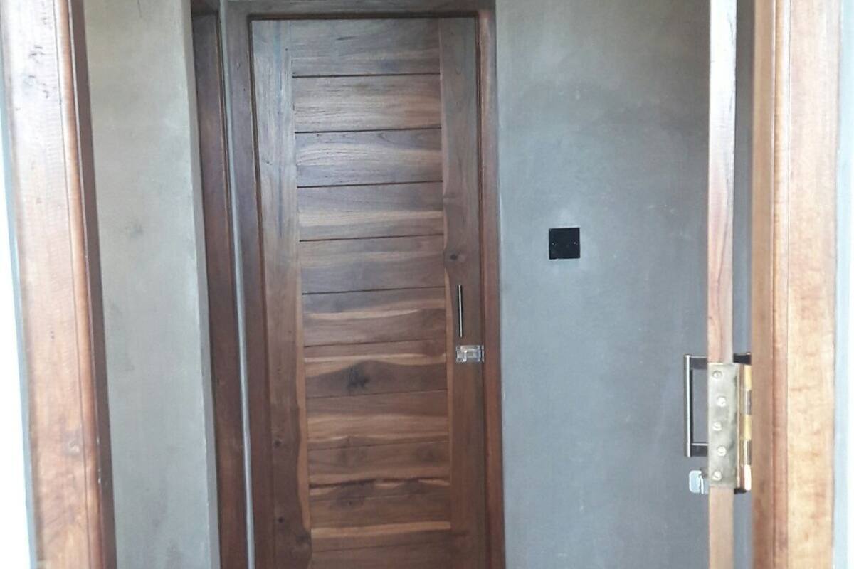 A wooden door with a metal handle and a small rectangular object on the wall to its right.