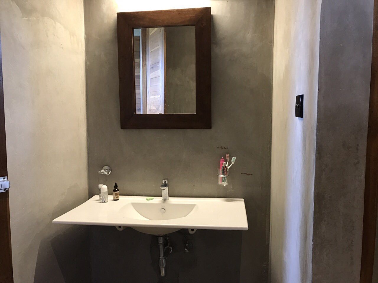 A bathroom with a white sink, two faucets, a mirror, and a soap dispenser.