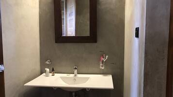 A bathroom with a white sink, two faucets, a mirror, and a soap dispenser.