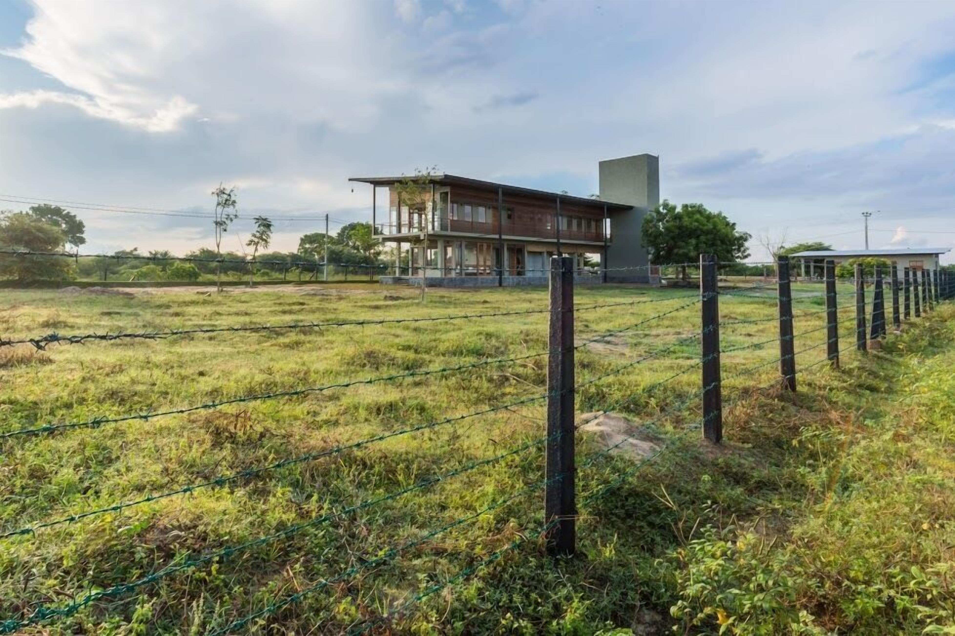 A fenced property with a building featuring a balcony and a modern design.