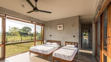 Un dormitorio moderno con dos camas, ventanas amplias y un ventilador de techo.