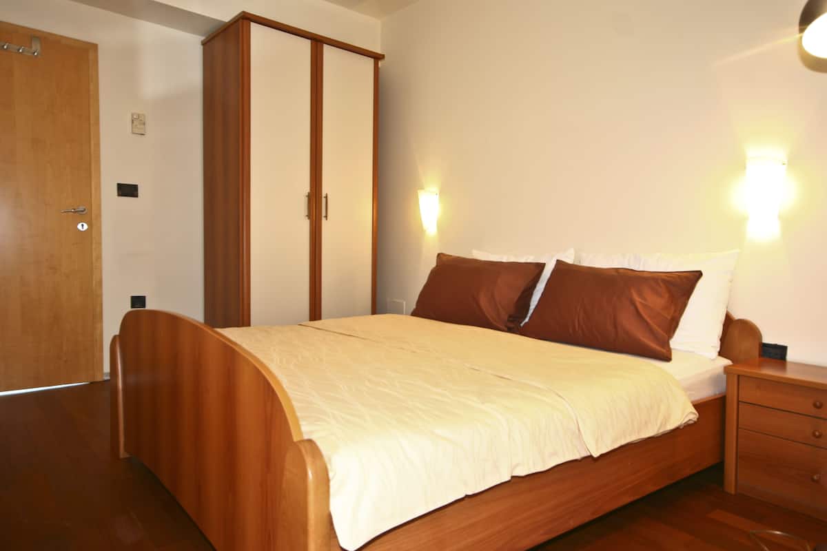 A bedroom with a wooden bed, a wardrobe, and a nightstand.