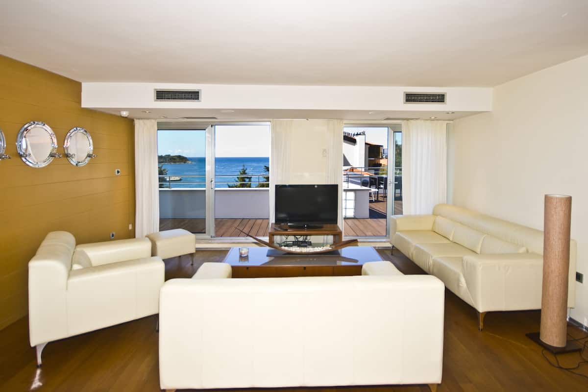 A living room with a TV, white sofas, and a wooden coffee table.