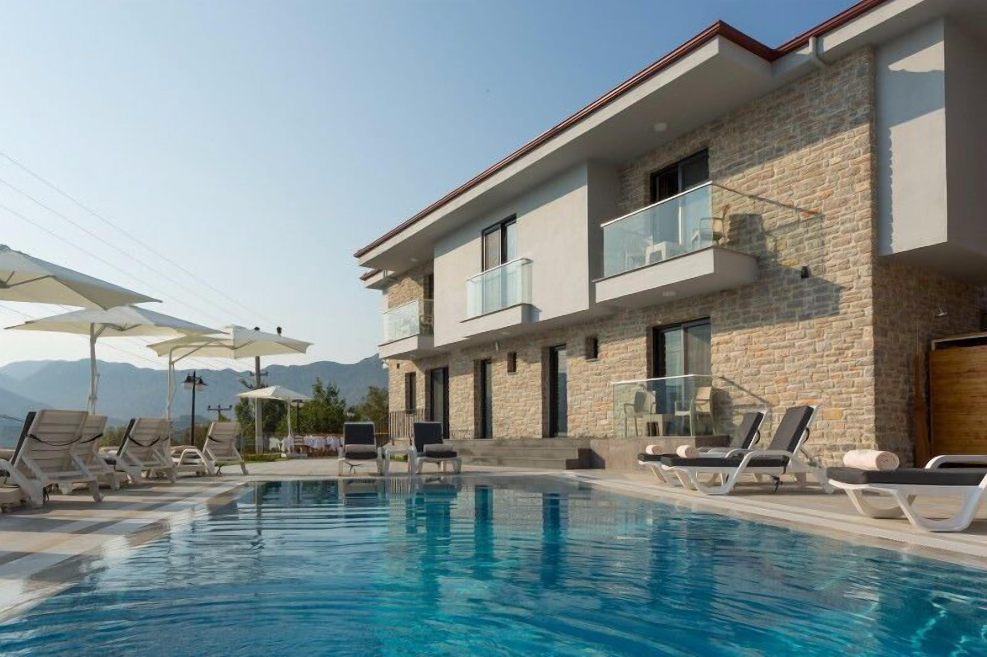 A modern building with a pool, stone facade, and balconies.