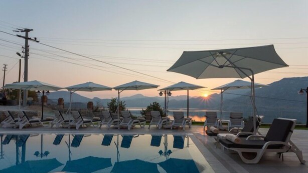 A poolside area with lounge chairs and umbrellas, a clear view of the sunset, and mountains in the background. - Aria Butik Otel (Marmaris)