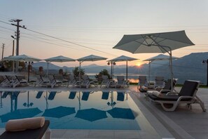 A poolside area with lounge chairs and umbrellas, a clear view of the sunset, and mountains in the background. - Aria Butik Otel (Marmaris)