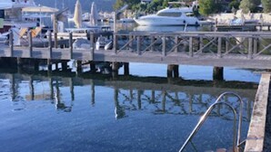A marina with boats docked, a clear water surface, and a metal ladder leading into the water. - Aria Butik Otel (Marmaris)